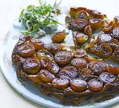 Caramelized onion tart with a savory glaze on a white plate.