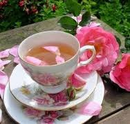 A delicate teacup with pink tea and rose petals, surrounded by pink roses.