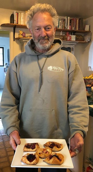 Man wearing a beige hoodie with a logo standing indoors.
