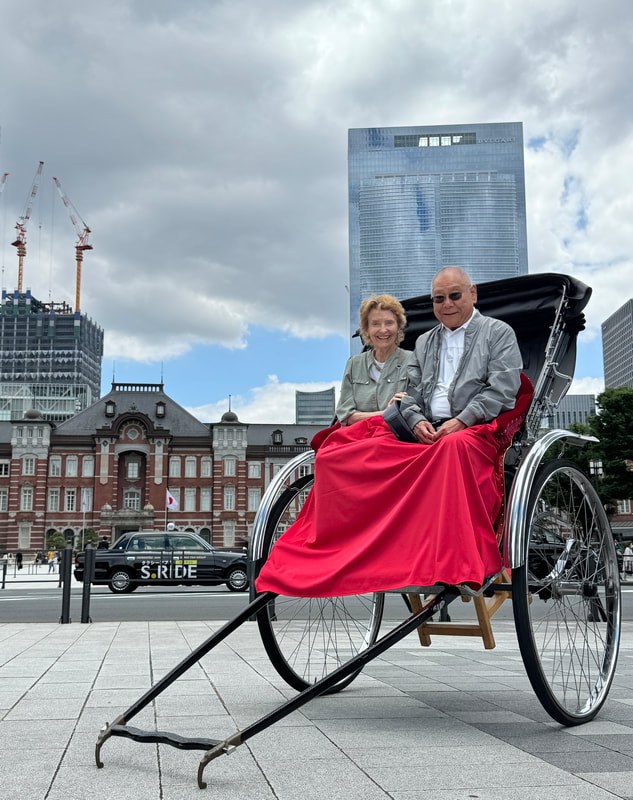 Elderly couple enjoying a ride on a traditional rickshaw in an urban setting.