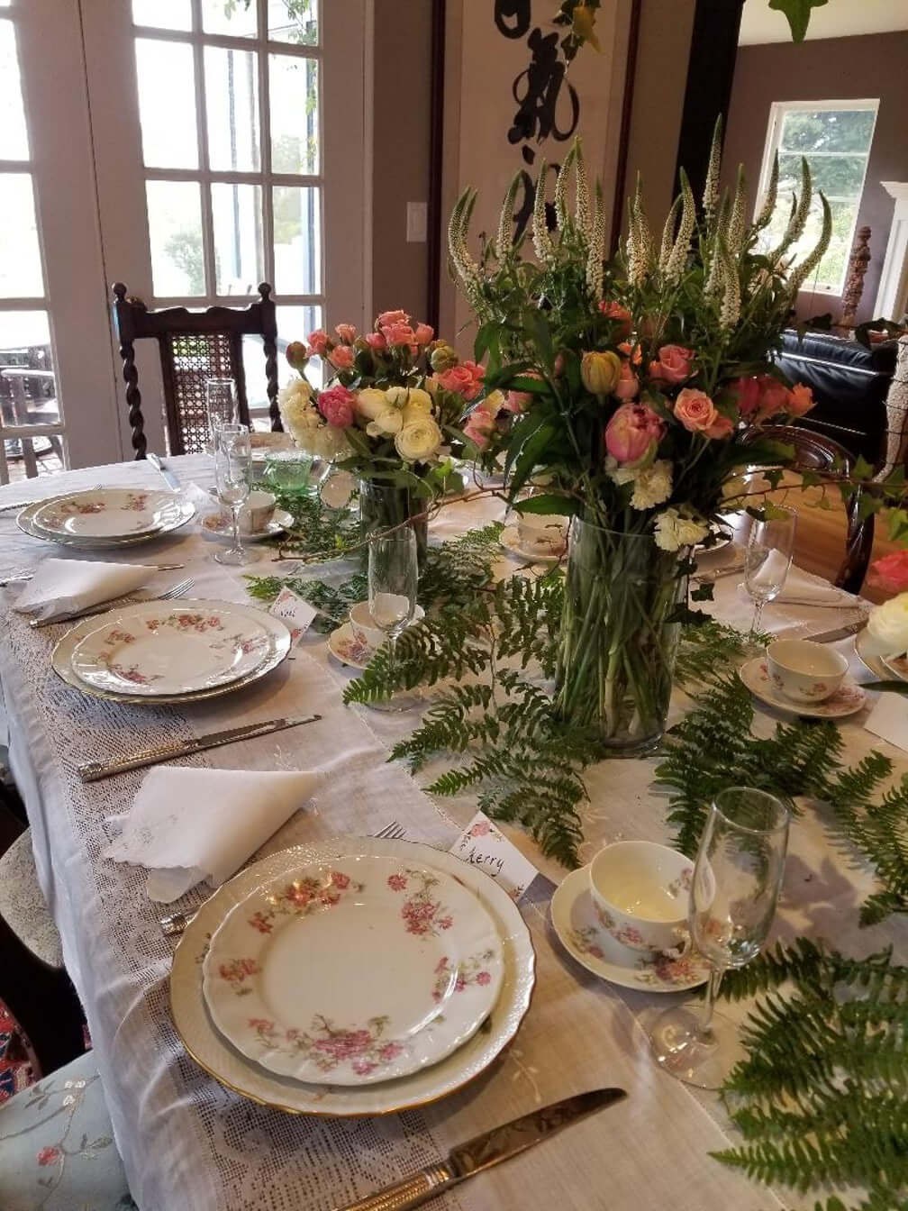 Elegant dining table set with floral arrangements and fine china.