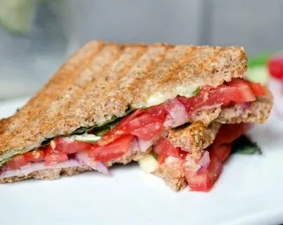Close-up of a grilled sandwich with tomato and greens.