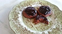Chocolate-glazed cookies on a decorative plate, one partially eaten.