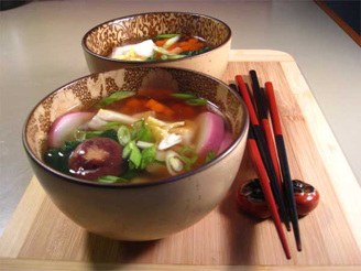 A bowl of colorful vegetable soup with chopsticks beside it.