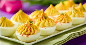 Deviled eggs topped with paprika and herbs on a plate.