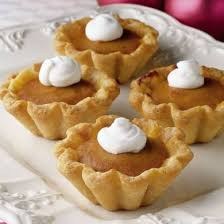 Mini pumpkin tarts topped with whipped cream on a decorative plate.