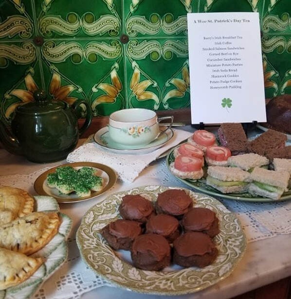 A tea setting with pastries, sweets, and a teapot on a decorative table.