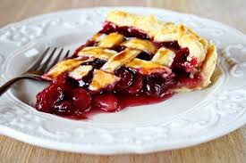 A slice of cherry pie with lattice crust on a white plate.
