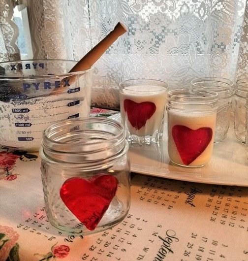 Glass jars decorated with red heart stickers on a table.