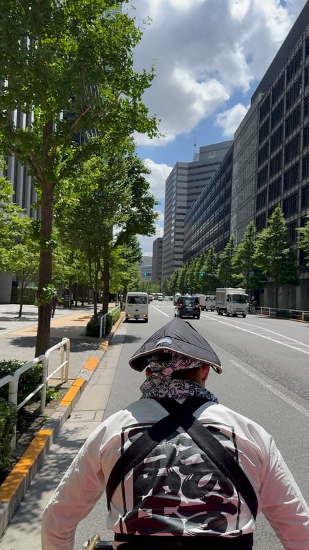 Urban street lined with trees and modern buildings under a partly cloudy sky.