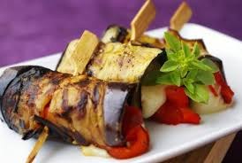 Grilled eggplant rolls stuffed with cheese and garnished with basil and red peppers.
