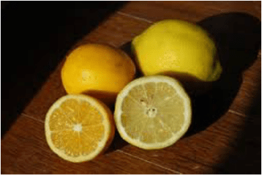 Two whole lemons and two lemon halves on a wooden surface.