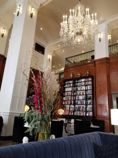 Elegant lobby with chandelier and bookshelf.