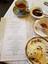 Afternoon tea setup with menu, scone, jam, and floral teacups.