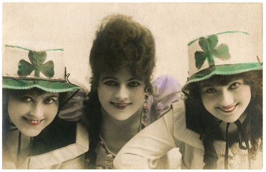 Three women wearing green and white hats, smiling together.