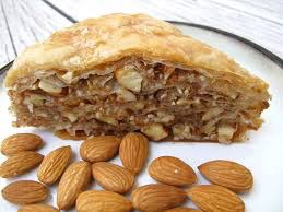 Close-up of a nut-filled baklava slice with almonds on the side.