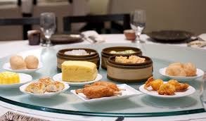 A table with dim sum dishes and drinks in a restaurant.