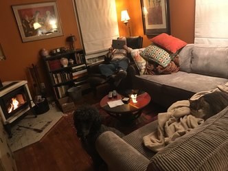 Cozy living room with a person relaxing on the couch and a dog nearby.