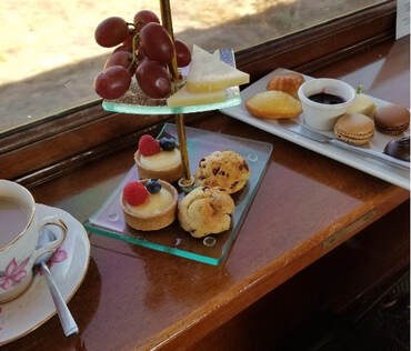 A selection of elegant desserts and fruit on a wooden table by the window.
