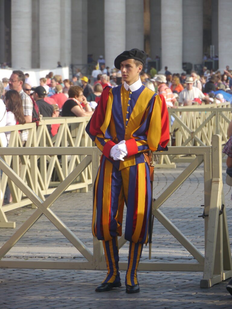 A Swiss Guard in traditional colorful uniform standing at attention.
