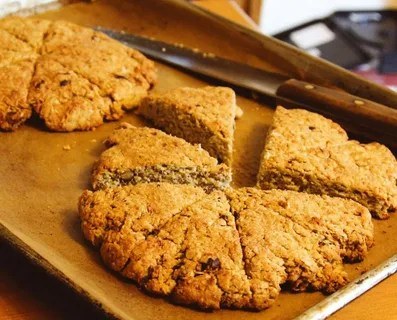 Freshly baked scones on a baking tray, partially sliced.