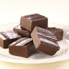 Chocolate fudge pieces stacked on a white plate.