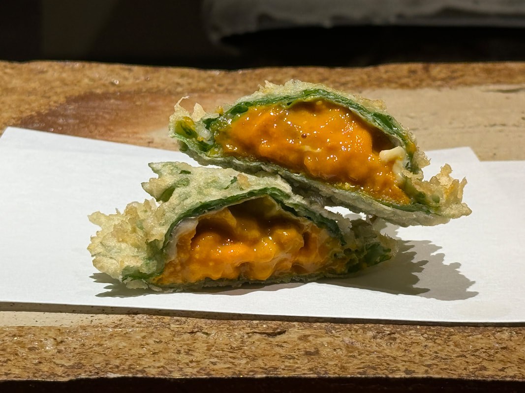 Tempura vegetables stuffed with a creamy orange filling on a white plate.