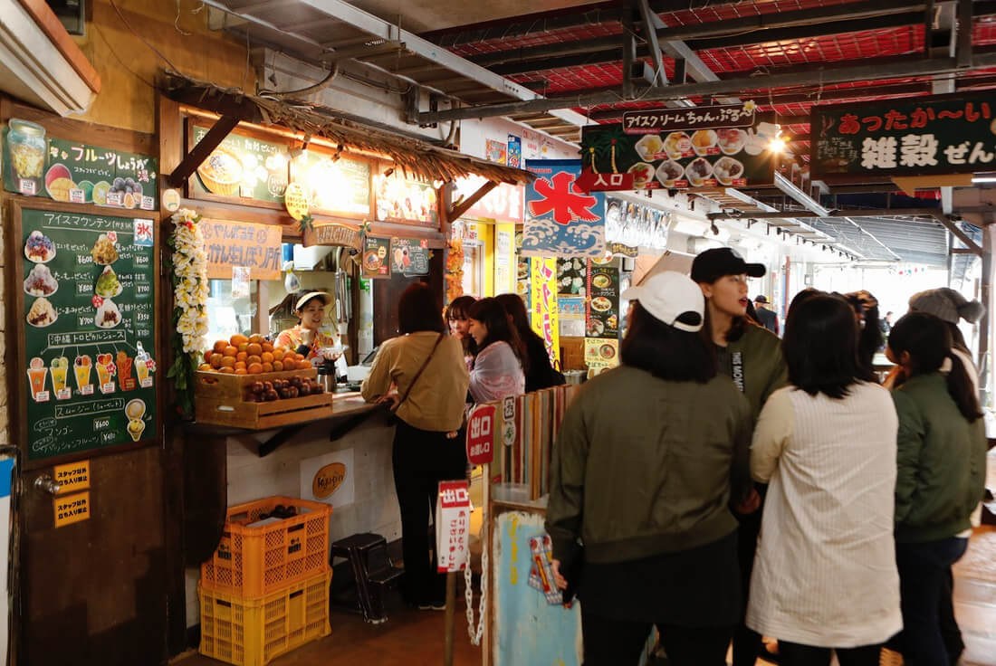 Busy indoor market with people shopping and socializing.