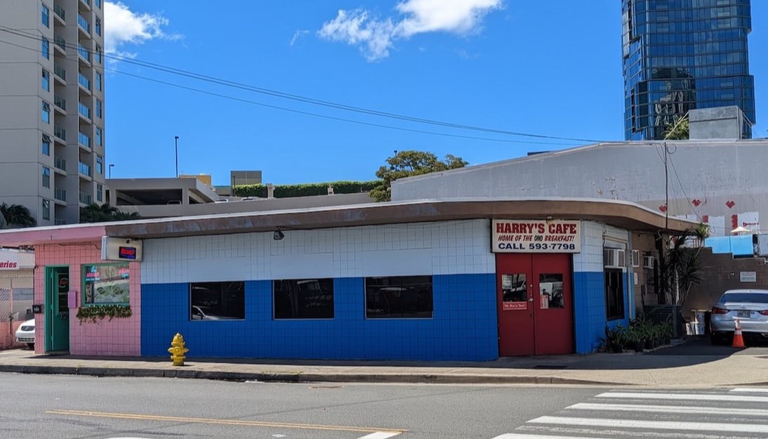 Blue and white building with a red door and sign on a street corner.