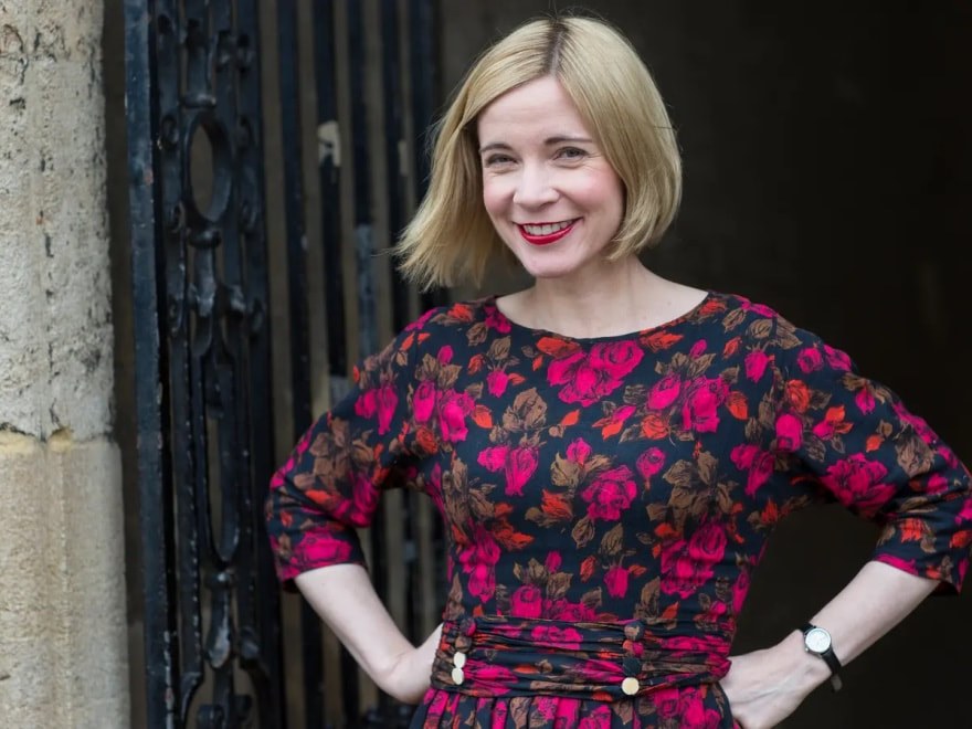 Smiling woman with blonde hair in a floral dress.