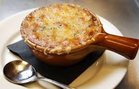 A bowl of cheesy French onion soup with melted cheese on top.