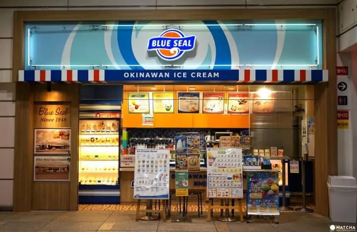 Front view of a Blue Seal Okinawan ice cream shop at night.