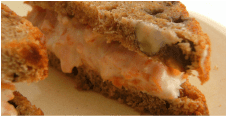 Close-up of a creamy, layered dessert with crumbly crust and orange filling.