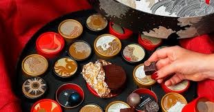 Hand selecting chocolates from assorted box.