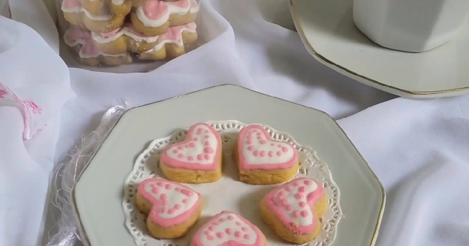 Heart-shaped cookies with pink icing on a white plate.