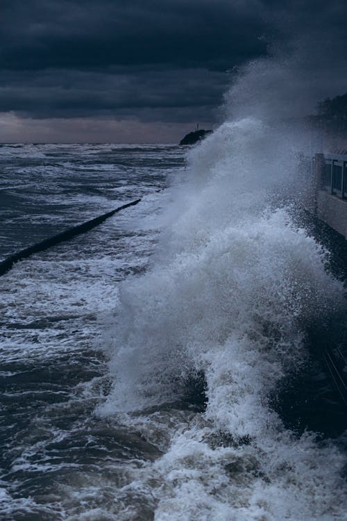 Powerful waves crashing against a seawall during a stormy night.