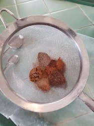 Metal sieve with white and brown powders inside.