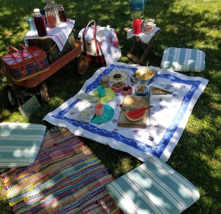 Outdoor picnic setup with traditional woven rugs and refreshments.