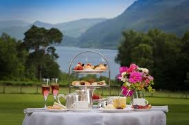 A serene lakeside tea setup with pastries and flowers.