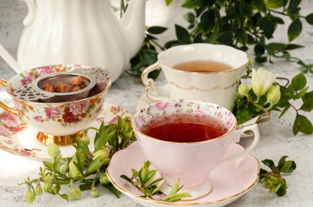 Elegant tea setup with floral china and fresh greenery.