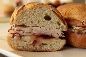 Close-up of a turkey sandwich with cranberry sauce on a bun.
