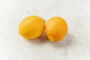 Two fresh lemons on a light surface.