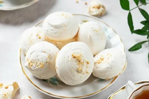 A plate of white meringue cookies with a crumbly topping.