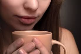 Woman holding a cup close to her lips, about to drink.