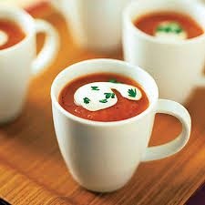 Cups of tomato soup with cream art and parsley garnish.