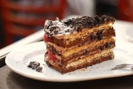 Slice of layered chocolate and strawberry cake on a white plate.