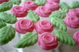 Pink rose-shaped frosting with green leaves on cupcakes.