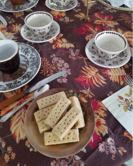 Tea cups and crackers on a floral tablecloth.