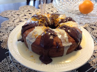 A bundt cake drizzled with chocolate and white icing on a plate.