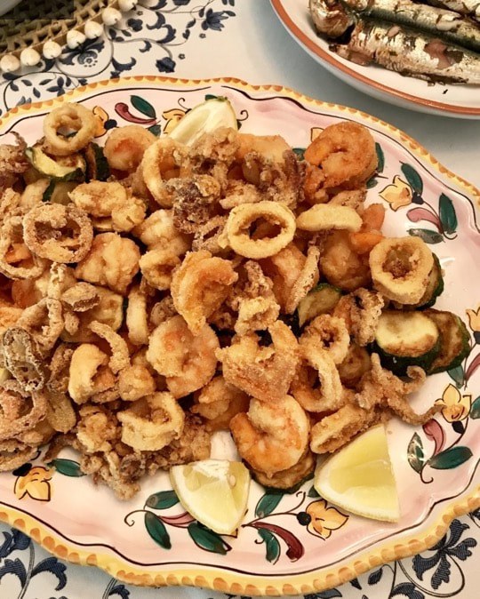 Plate of assorted fried seafood and vegetables with lemon wedges.
